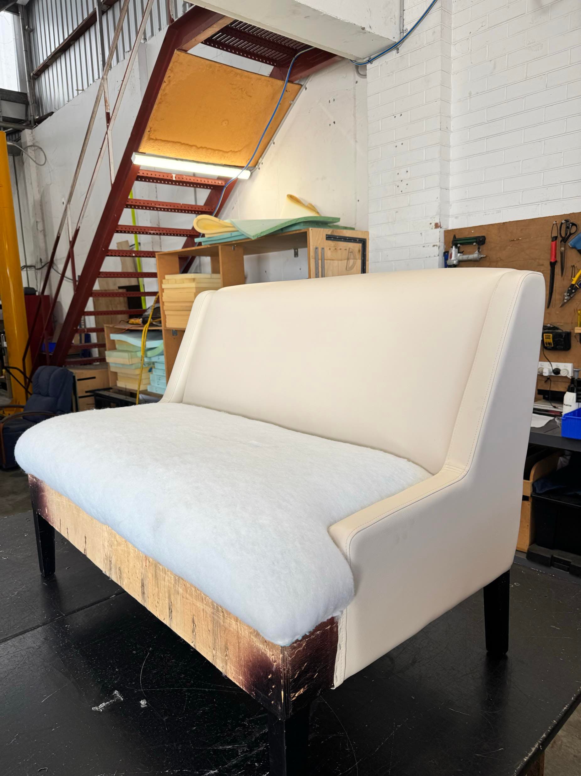 Banquette settee frame with exposed timber and batting in workshop