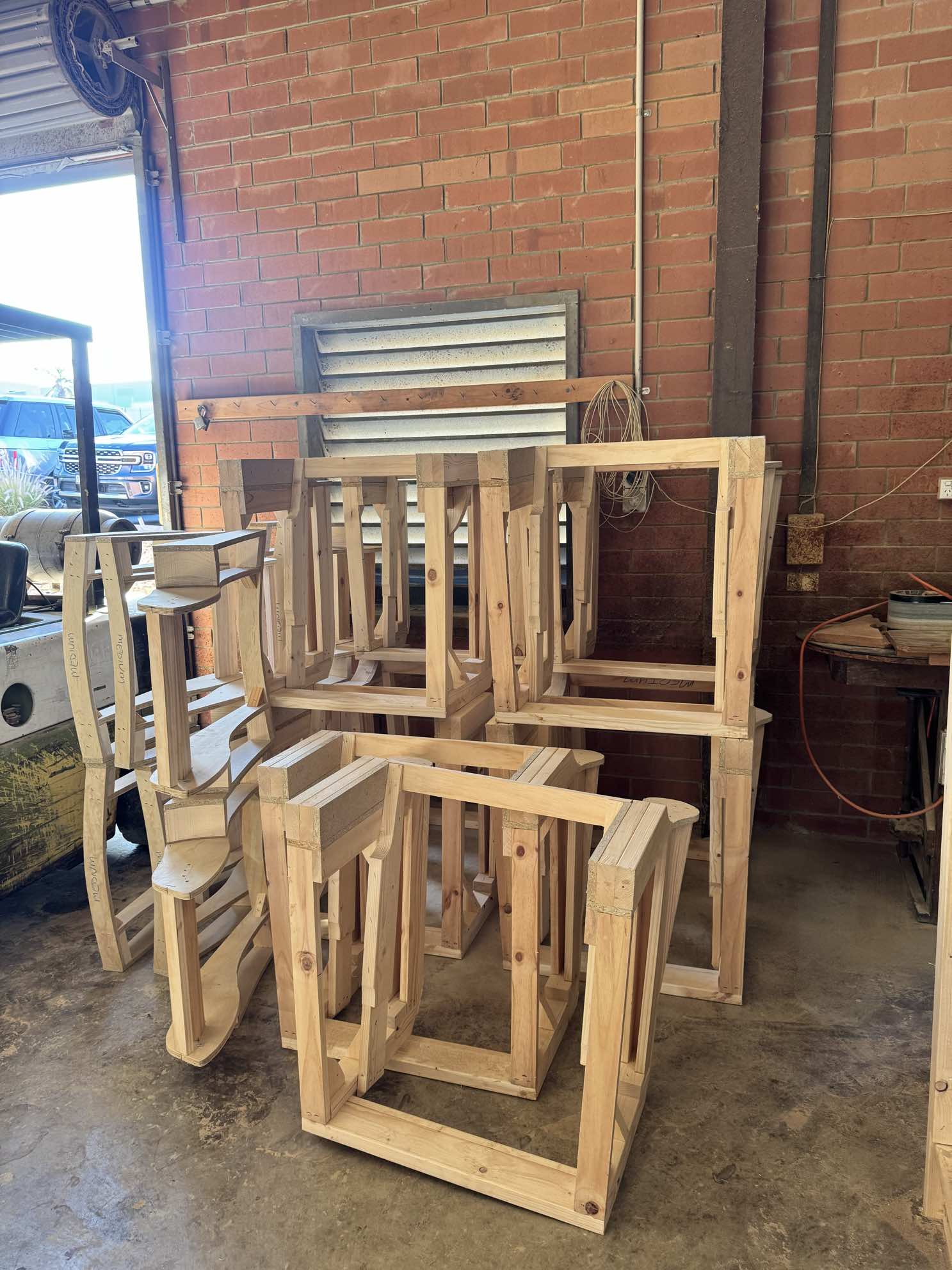 Multiple dining chair frames stacked in workshop